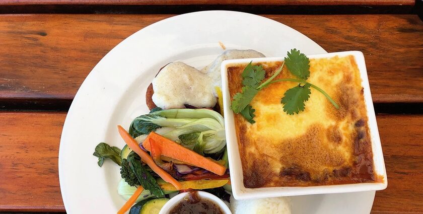 Traditional South African Bobotie dish is served in a baking dish with bay leaves on top.