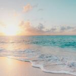 A breathtaking view of a sea with turquoise waters and sandy shores during the evening.