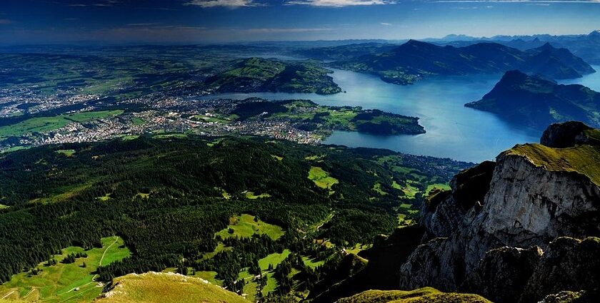 Breathtaking aerial view of lush green valleys, forested hills, and a serene lake
