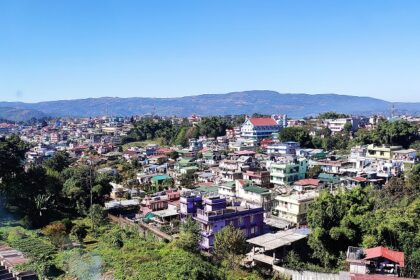 Shillong from above with distant buildings, green trees and clouds in the blue sky