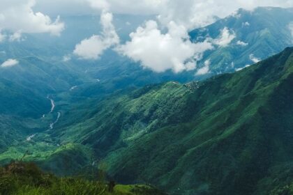 West Khasi hills in Meghalaya with distant buildings, greenery, mountains and clouds.