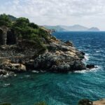 Scenic Alanya beach with rock cliffs and greenery, ideal places to visit near Antalya.
