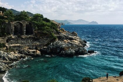 Scenic Alanya beach with rock cliffs and greenery, ideal places to visit near Antalya.