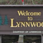 A welcome sign in northern Lynnwood, Washington, surrounded by ferns and mosses.