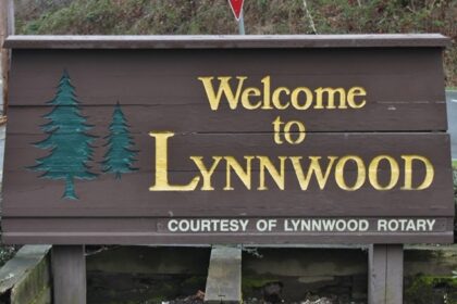 A welcome sign in northern Lynnwood, Washington, surrounded by ferns and mosses.