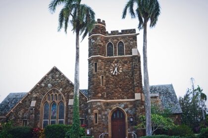 Makawao Union Church surrounded by tall trees under a clear sky in Upcountry Maui, one of the best things to see in Makawao.