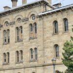 Historic three-story stone building with arched windows, fence, and trees, one of the best things to see in Old Cairo.