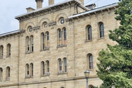 Historic three-story stone building with arched windows, fence, and trees, one of the best things to see in Old Cairo.