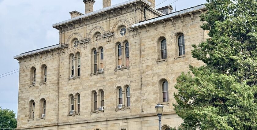 Historic three-story stone building with arched windows, fence, and trees, one of the best things to see in Old Cairo.