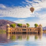 The scenic view of the Jal Mahal in Jaipur, surrounded by calm waters and green hills, during long weekends in 2025 in India.
