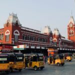 Image of Chennai where colourful yellow autos are parked near a red stunning architecture building