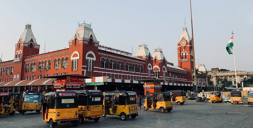Image of Chennai where colourful yellow autos are parked near a red stunning architecture building