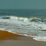 A serene view of Elliot’s beach with waves crashing over golden sand, one of the most beautiful places to visit near Chennai in September.
