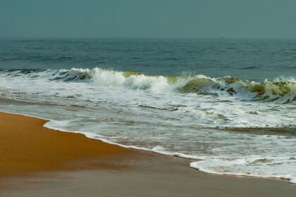 A serene view of Elliot’s beach with waves crashing over golden sand, one of the most beautiful places to visit near Chennai in September.