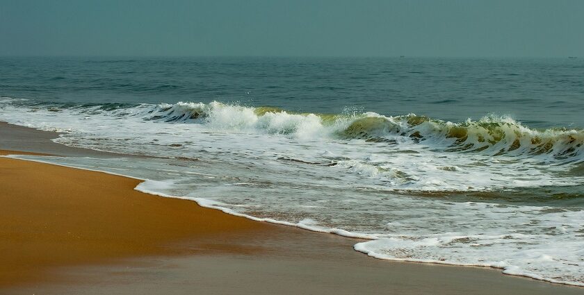 A serene view of Elliot’s beach with waves crashing over golden sand, one of the most beautiful places to visit near Chennai in September.