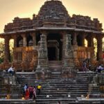 Ancient stone temple with intricate carvings gazing out to a stepped water tank beneath the sky