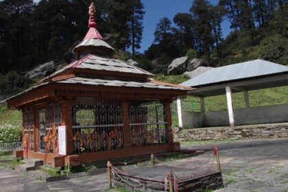 Small wooden temple with intricate carvings set amid lush green hills and pine trees Viewers of this file can see comments and suggestions