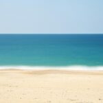 Sandy shore of Tithal Beach with calm waters, one of the top places to visit near Surat for 1 day.