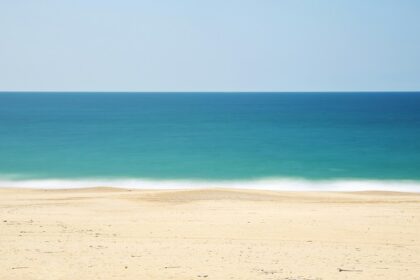 Sandy shore of Tithal Beach with calm waters, one of the top places to visit near Surat for 1 day.