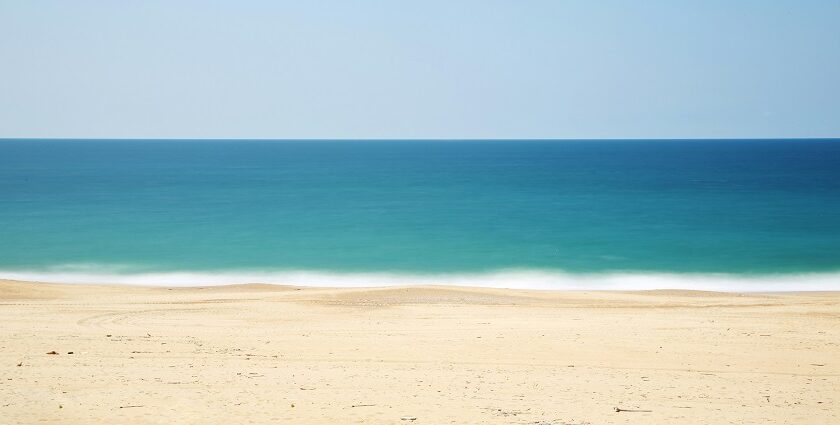 Sandy shore of Tithal Beach with calm waters, one of the top places to visit near Surat for 1 day.