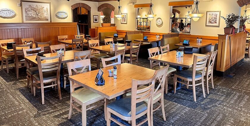 A well-lit restaurant dining room with many wooden tables and chairs, and booths, one of the best Indian restaurants in Singapore, Little India.