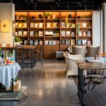 An interior view of Park Restaurant with a wooden table, chair, and a wall-mounted bookshelf, one of best restaurants in Darjeeling.