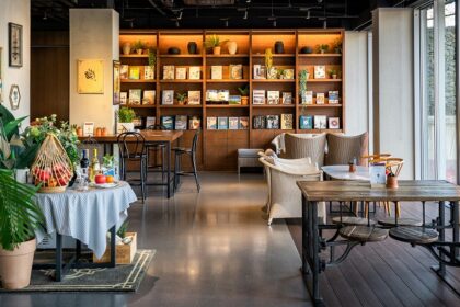 An interior view of Park Restaurant with a wooden table, chair, and a wall-mounted bookshelf, one of best restaurants in Darjeeling.
