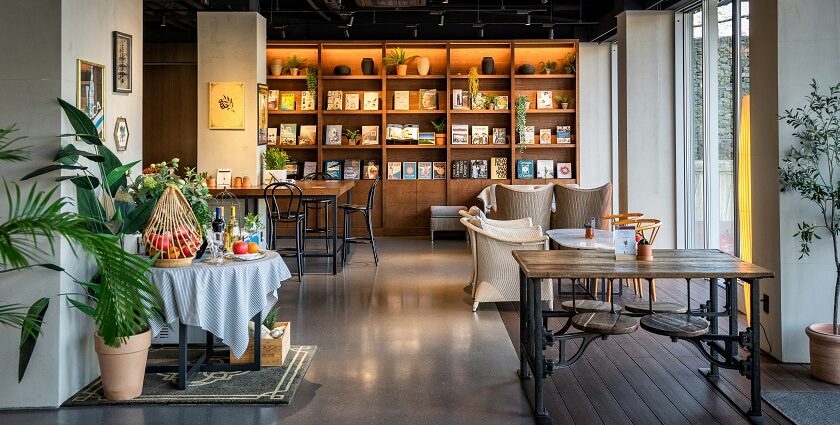 An interior view of Park Restaurant with a wooden table, chair, and a wall-mounted bookshelf, one of best restaurants in Darjeeling.