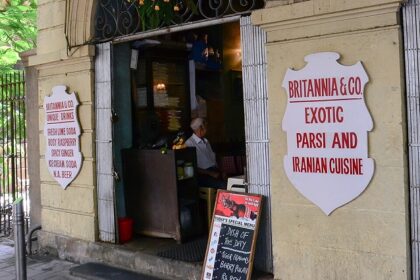 Front of Café du Commerce in Belley with black awning, wooden barrels, and seating, one of the best cafes in Kalimpong.