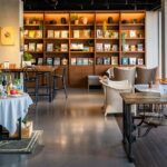 Interior view of Cafe Royale with wooden tables, chairs, and bookshelf, one of the best cafes in Siliguri.