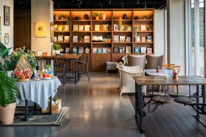 Interior view of Cafe Royale with wooden tables, chairs, and bookshelf, one of the best cafes in Siliguri.