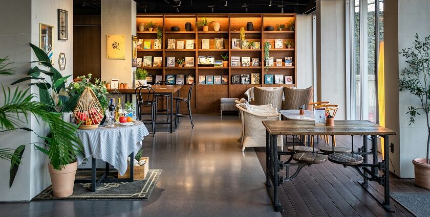 Interior view of Cafe Royale with wooden tables, chairs, and bookshelf, one of the best cafes in Siliguri.