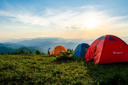 Two tents on a grassy hilltop under cloudy skies, perfect for camping in Karnataka.