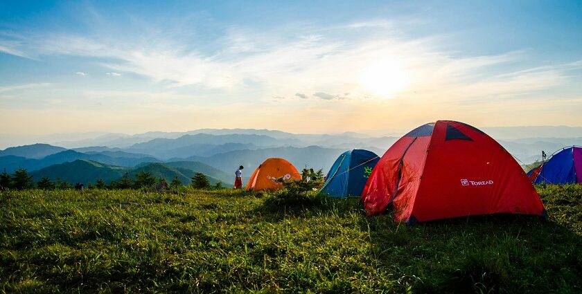 Two tents on a grassy hilltop under cloudy skies, perfect for camping in Karnataka.