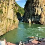 Koteshwar Mahadev Temple surrounded by scenic caves in Uttarakhand along river.