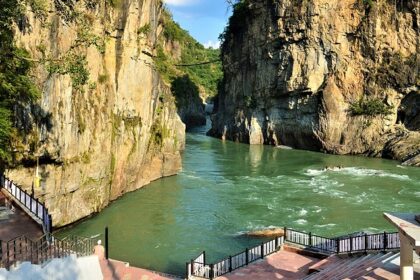 Koteshwar Mahadev Temple surrounded by scenic caves in Uttarakhand along river.