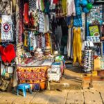 A lively outdoor market with vendor stalls and people walking around a city square.