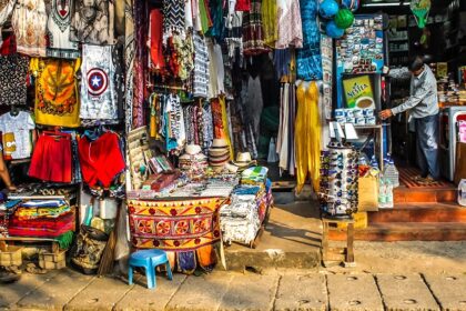 A lively outdoor market with vendor stalls and people walking around a city square.