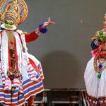 Two people in traditional clothes performing at a vibrant harvest festival of Kerala.