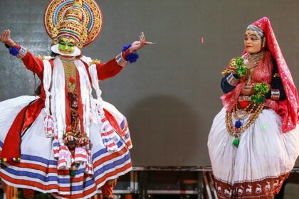 Two people in traditional clothes performing at a vibrant harvest festival of Kerala.