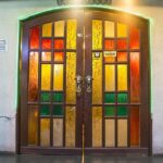 A welcoming entrance with a stained-glass door and decorative Indian dancer panels, in one of the Indian restaurants in Kuala Lumpur.