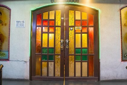 A welcoming entrance with a stained-glass door and decorative Indian dancer panels, in one of the Indian restaurants in Kuala Lumpur.