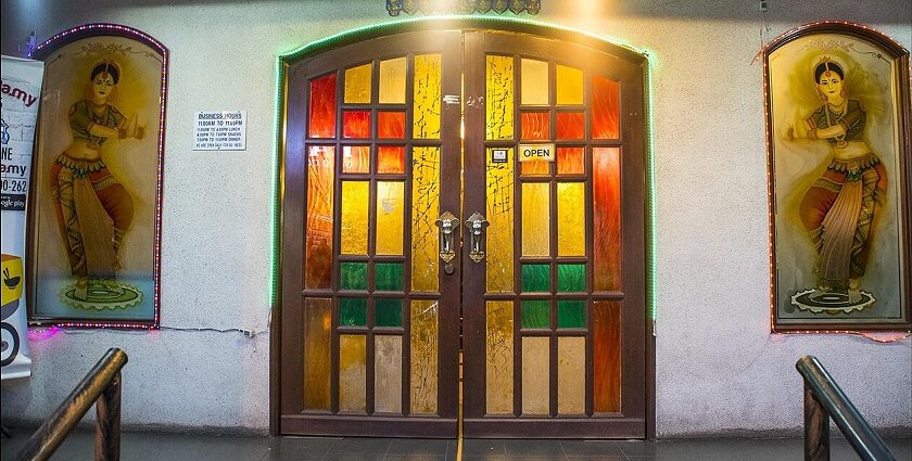 A welcoming entrance with a stained-glass door and decorative Indian dancer panels, in one of the Indian restaurants in Kuala Lumpur.
