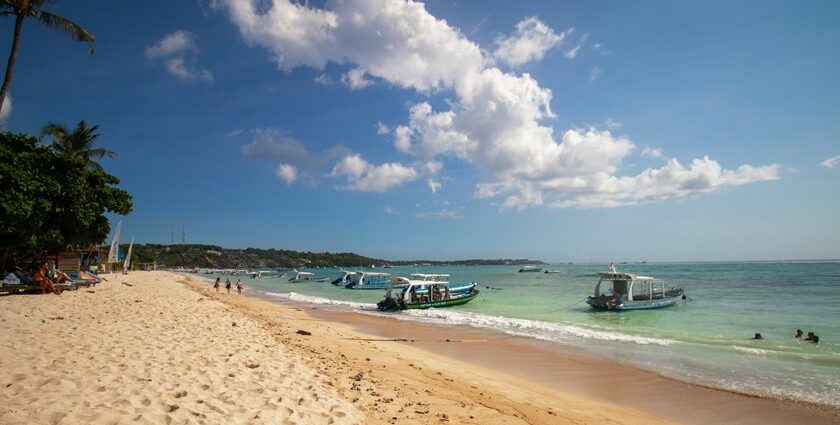 Sandy shore and calm waters with boats docked at Nusa Lembongan, one of the best islands in Bali.