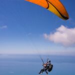 Paragliding in Andaman over a beach with lush greenery and turquoise waters below.