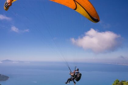 Paragliding in Andaman over a beach with lush greenery and turquoise waters below.