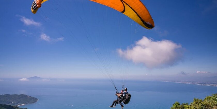 Paragliding in Andaman over a beach with lush greenery and turquoise waters below.