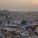 Pushkar Mela from above with multiple small tents, people visiting and mountains.