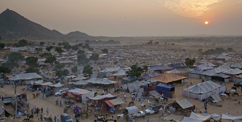 Pushkar Mela from above with multiple small tents, people visiting and mountains.