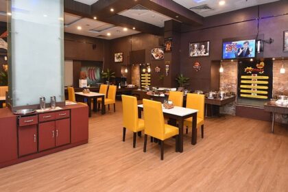 Interior of a modern restaurant in Siliguri with yellow chairs, wood flooring, buffet area